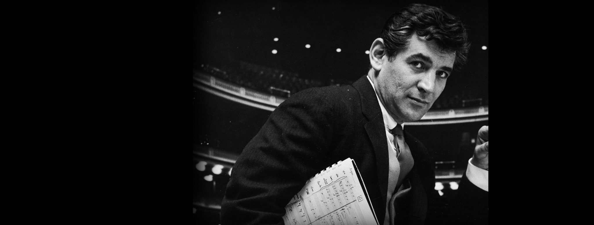 Composer Leonard Bernstein, holding musical score with lighted auditorium behind him. / Credit: Gordon Parks/The LIFE Picture Collection/Getty Images